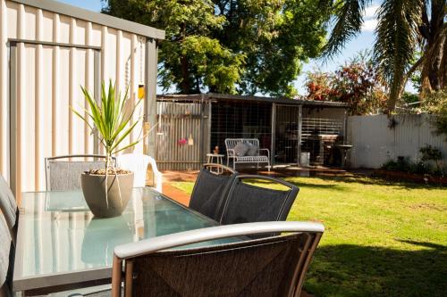 a glass table with chairs and a potted plant at Bidgee Motor Inn in Hay