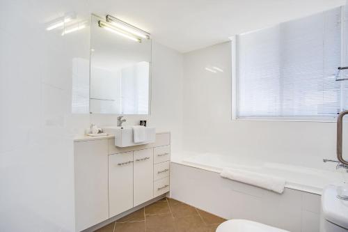 a white bathroom with a tub and a sink at Mantra Twin Towns in Tweed Heads