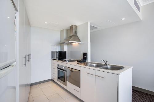 a kitchen with white cabinets and a sink at Mantra Twin Towns in Tweed Heads