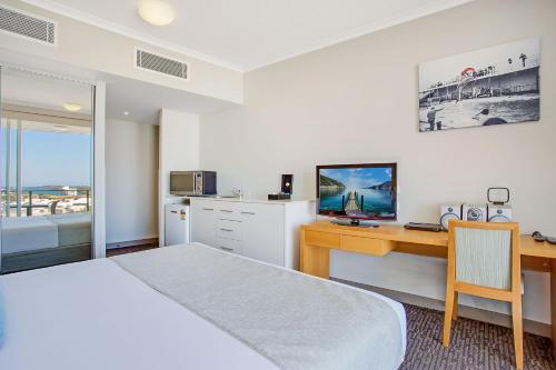 a bedroom with a bed and a desk with a television at Mantra Twin Towns in Tweed Heads