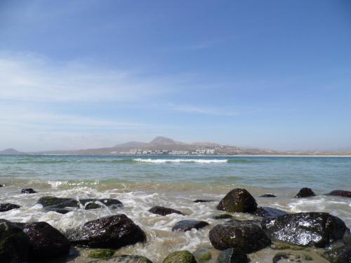 a beach with rocks and the ocean with mountains in the background at Cabañas Urmeneta Sur in Tongoy