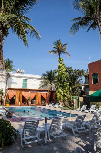 a swimming pool with lounge chairs and palm trees at Hotel Vicino al Mare - Frente mar in Guarujá