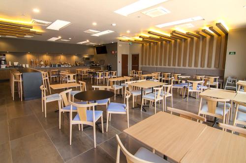 a restaurant with wooden tables and chairs and a bar at City Express Plus by Marriott Ciudad de México Mundo E in Mexico City