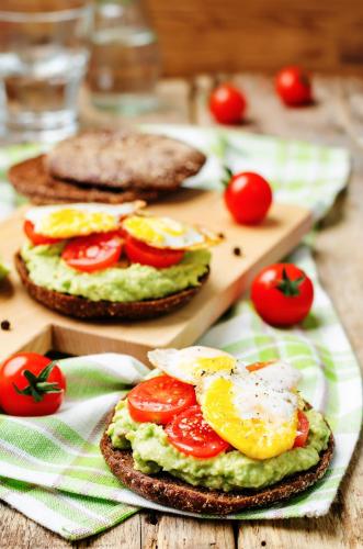 a sandwich with eggs and tomatoes on a table at Oaks Brisbane Festival Suites in Brisbane