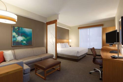 a large hotel room with a bed and a couch at Hyatt Place St. Louis/Chesterfield in Chesterfield