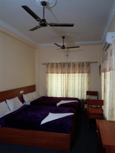 1 dormitorio con 2 camas y ventilador de techo en Hotel Daisy Park, en Bhairāhawā