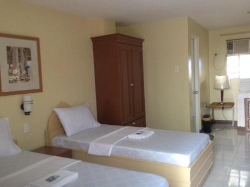 a room with two beds and a cabinet at Danel Pensionne House in Tacloban