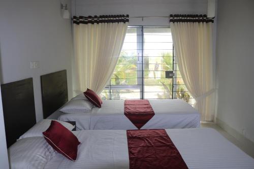 JaliapāraにあるSunset Serenityの大きな窓のある寝室にベッドが2つある