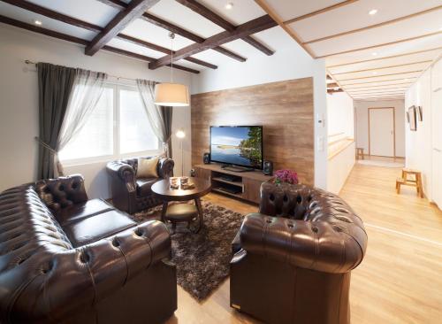a living room with leather furniture and a flat screen tv at Vuokatin Aateli Villa Keisari in Vuokatti