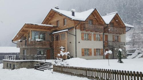 a wooden house in the snow with snow at Appartamento Clelia in Pellizzano