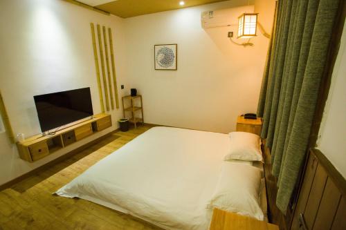 a bedroom with a bed and a flat screen tv at Wally House青山惠风民宿 in Zhangjiajie