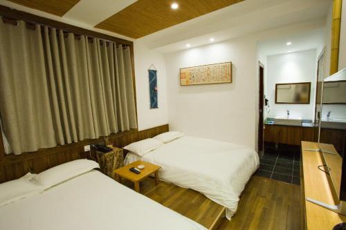 a hotel room with two beds and a table at Wally House青山惠风民宿 in Zhangjiajie
