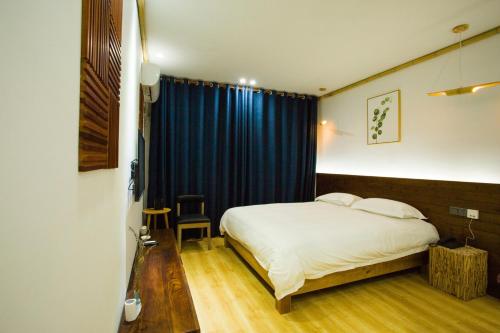 a bedroom with a bed and a blue curtain at Wally House青山惠风民宿 in Zhangjiajie
