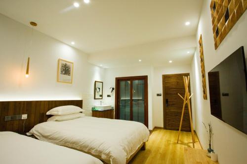 a bedroom with two beds and a flat screen tv at Wally House青山惠风民宿 in Zhangjiajie