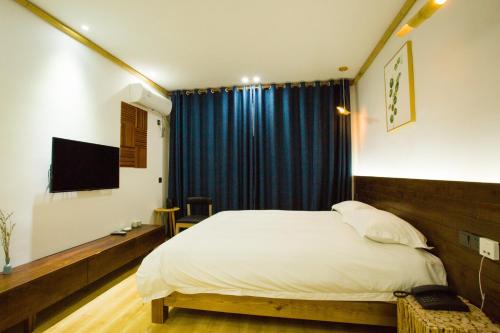 a bedroom with a bed and a blue curtain at Wally House青山惠风民宿 in Zhangjiajie