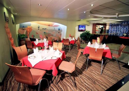 a restaurant with red tables and chairs and a cow mural at La Vinci Hotel in Dhaka