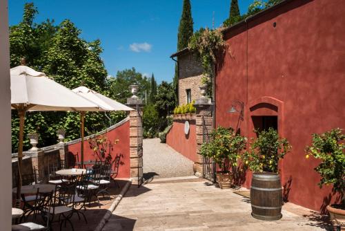 an outdoor patio with tables and chairs and a red building at Borgo Grondaie in Siena
