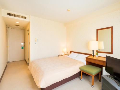 a bedroom with a bed and a desk and a television at Yatsushiro Grand Hotel in Yatsushiro