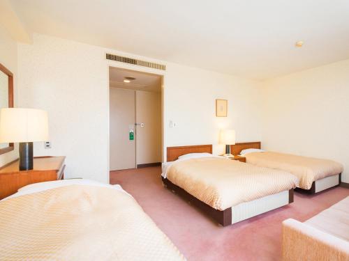 Habitación de hotel con 2 camas y 2 lámparas en Yatsushiro Grand Hotel, en Yatsushiro