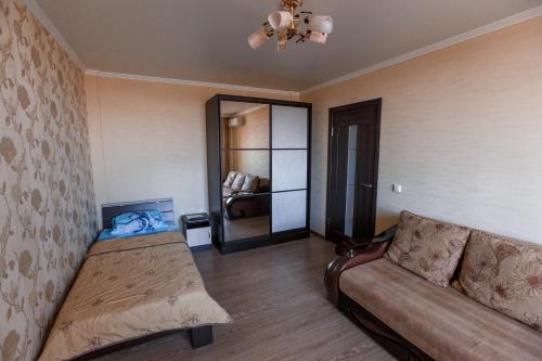 クラスノダールにあるАпартаменты на Красной площадиのベッド1台、ソファ、鏡が備わる客室です。
