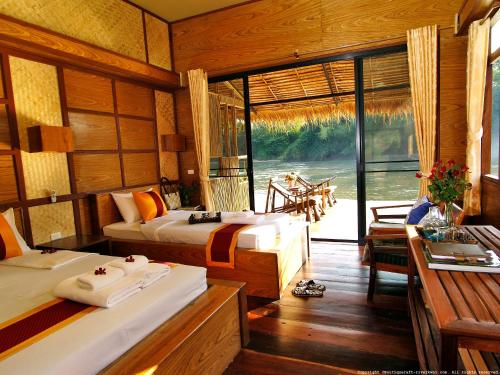 1 dormitorio con 2 camas y balcón con vistas. en Boutique Raft Resort, River Kwai, en Sai Yok