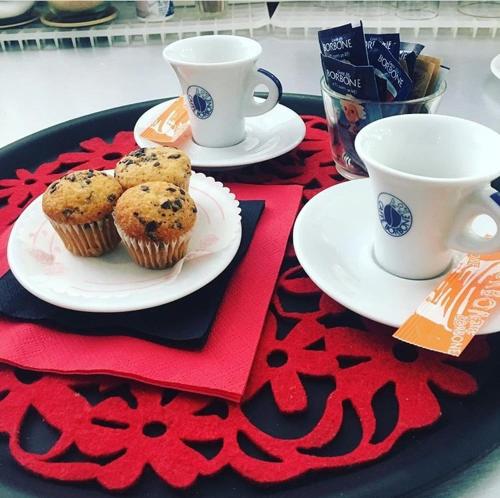 ein Tisch mit zwei Tassen und Muffins auf einem Tisch in der Unterkunft Hotel Hermitage in Qualiano