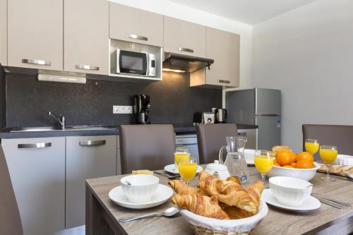 a kitchen with a table with bread and orange juice at Résidence Odalys Front de Neige in Plagne Villages
