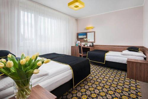 a hotel room with two beds and a vase of flowers at Dom Wczasowy VIS in Jastrzębia Góra