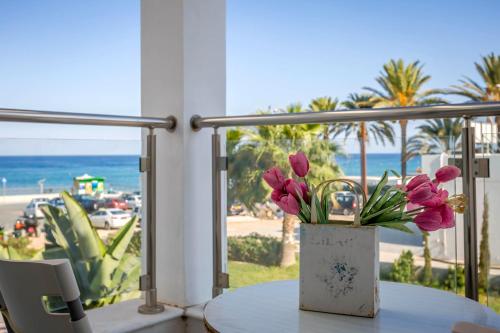 a table with a vase of pink flowers on a balcony at Villa Nora in Protaras
