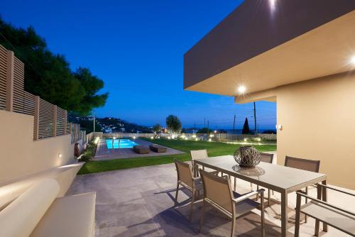 a patio with a table and chairs and a pool at Elaia Luxury Suites Lagonisi in Lagonissi