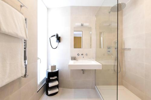 a bathroom with a sink and a glass shower at Hôtel Mathis Elysées in Paris