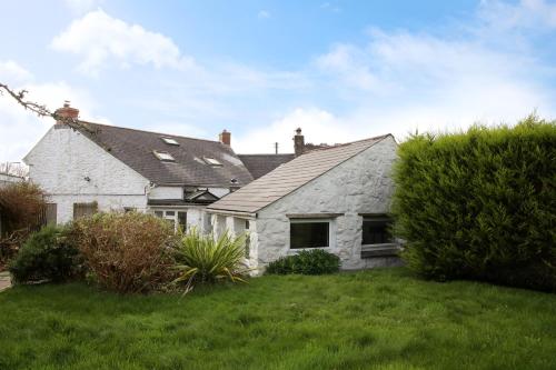 uma casa de pedra branca com um jardim verde em Little Trewin em Helston