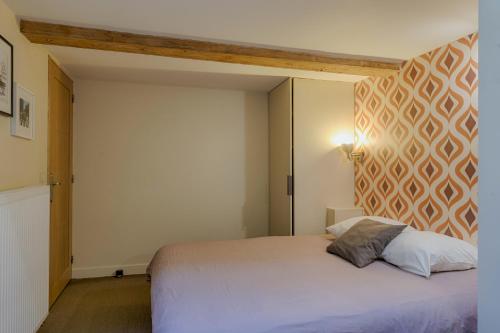 - une chambre avec un lit blanc et une tête de lit géométrique dans l'établissement L'Imprimerie, à Lyon