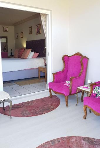 a bedroom with a bed and two chairs and a table at 1AA Wilhelmina Luxury Suites in Franschhoek