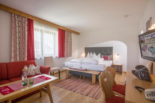a hotel room with a bed and a living room at Hotel Landhaus Zillertal in Fügen