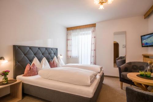 a bedroom with a large bed and a living room at Hotel Landhaus Zillertal in Fügen