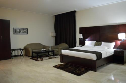 a hotel room with a large bed and a chair at De Santos Hotel in Agege