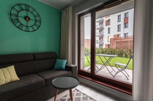 a living room with a couch and a clock on the wall at GRANO APARTMENTS Gdańsk Motława SPA & Wellness in Gdańsk