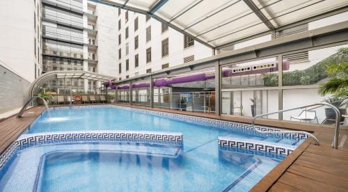 a large swimming pool in the middle of a building at Ilunion Málaga in Málaga