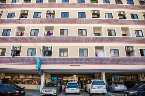 a large building with cars parked in a parking lot at Baan Romdee in Nonthaburi