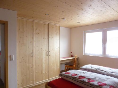 Schlafzimmer mit Holzschränken, einem Bett und einem Fenster in der Unterkunft Hochtalblick in Bernau im Schwarzwald