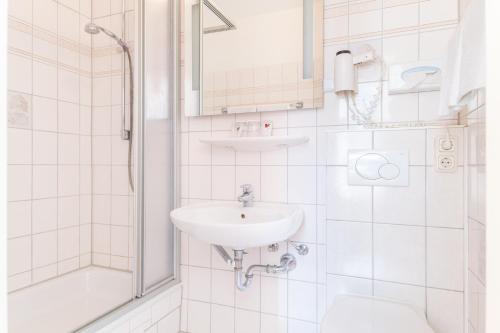 a white bathroom with a sink and a shower at Hotel Bayernland in Munich