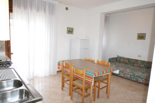 a dining room with a table with chairs and a couch at Condominio York in Lido di Jesolo