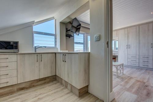 a kitchen with wooden cabinets and a large window at Marine Manor in Mossel Bay