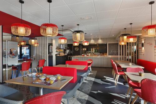 a restaurant with tables and chairs and chandeliers at ibis Le Mans Est Pontlieue in Le Mans