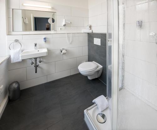 a white bathroom with a toilet and a sink at Hotel Weidenhof in Regensburg