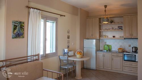 a kitchen with a table and a white refrigerator at Muses Villas in Finikounta