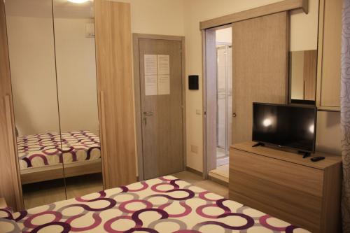 a room with a television and a bedroom with a bed at B&B Castello Salvaterra in Iglesias