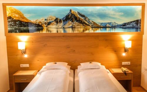 two beds in a room with a painting on the wall at Pension Iris in Lech am Arlberg