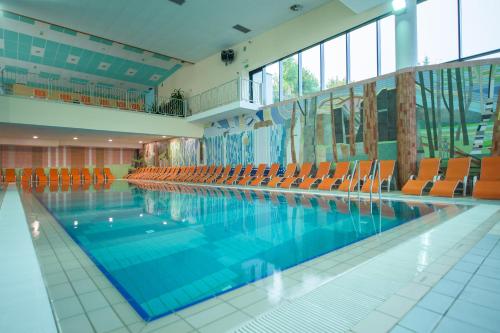 a large swimming pool with orange chairs in a building at Glamping Sun Valley Bioterme in Mala Nedelja